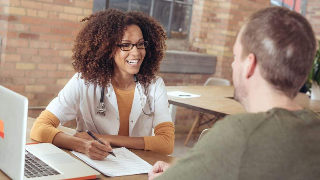 Doctor taking notes sitting with a patient