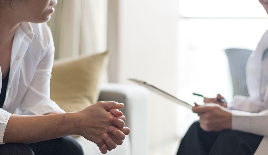 A therapist with paper and pen sitting with a patient