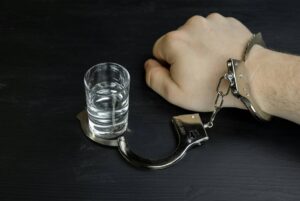 A man's hand chained to a glass of vodka